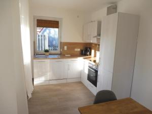 a kitchen with white cabinets and a window at Ferienhäuser Loppersum in Hinte +8 photos