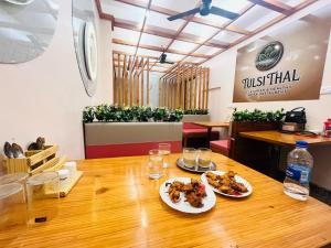 a restaurant with two plates of food on a wooden table at SHRI ANANDAM Inn in Isauli