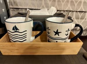 two coffee mugs sitting on a wooden tray at Baannira บ้านนิรา in Ban Sam Kong