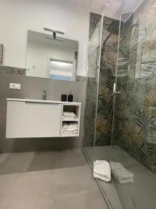 ein Badezimmer mit Dusche, Waschbecken und Spiegel in der Unterkunft Casa Vacanza Da Angela & Corrado in Pozzallo