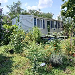 a caravan in a garden with plants at Kék-Fehér Mobilház in Zsombó