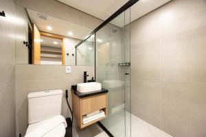 a bathroom with a toilet and a glass shower at SOL - Flats Av Cauaxi By Anora Spaces in Barueri +15 photos