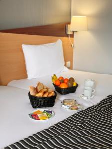 two baskets of fruit and bread on a bed at Kyriad Hotel Dijon Centre Gare in Dijon +39 photos