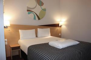 a hotel room with a bed with a black and white blanket at Kyriad Hotel Dijon Gare in Dijon