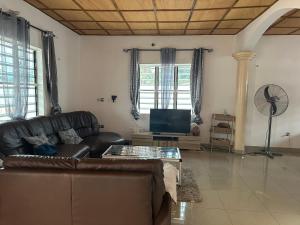 ein Wohnzimmer mit einem Ledersofa und einem TV in der Unterkunft Maison de vacances Calavi séminaire in Abomey-Calavi