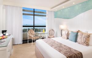 a hotel room with a bed and a table and chairs at The Grand Oasis Cancun - All Inclusive in Cancún +35 photos