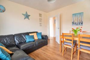 a living room with a black leather couch and a table at Finest Retreats - Llys Llewellyn in Kinmel Bay