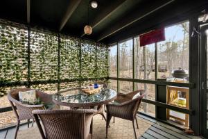 a room with a glass table and chairs and windows at Zen Vibe w Fireplace Grill Deck & Screened Porch in Hedgesville