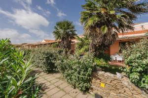 a house with palm trees and a stone pathway at Le Tonnare - Relaxing house near the sea in Stintino