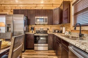 a kitchen with wooden cabinets and stainless steel appliances at Blue Bear Splash in Pigeon Forge +32 photos