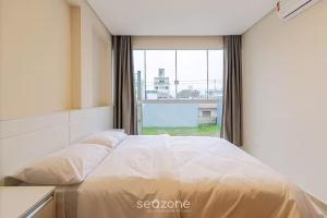 ein Bett in einem Zimmer mit einem großen Fenster in der Unterkunft Casa 2Q c churrasq a 600m do mar RVL118 in Canto Grande