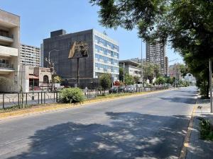 an empty street in a city with a building at Encantador e Iluminado Departamento, Ñuñoa in Santiago +4 photos