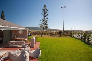 a patio with white couches and a grass yard at Beachfront Kite House No 1 Shaapenzicht 1 in Langebaan