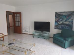 a living room with a tv and a blue chair at Casa Tété in Faro