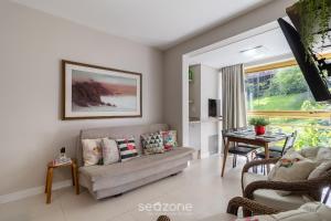 een woonkamer met een bank en een tafel bij Apto Vista Mar 240m da Praia em Jurerê IDO207 in Florianópolis