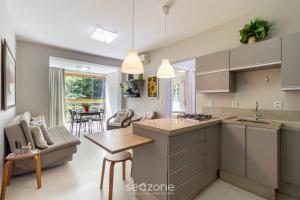 een keuken en woonkamer met een bank en een tafel bij Apto Vista Mar 240m da Praia em Jurerê IDO207 in Florianópolis