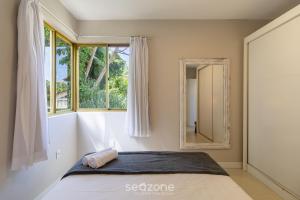 een slaapkamer met een bed met een spiegel en een raam bij Apto Vista Mar 240m da Praia em Jurerê IDO207 in Florianópolis +15 foto's