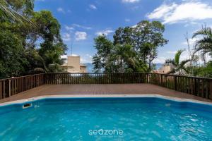 een zwembad met een houten hek en een blauw zwembad bij Apto Vista Mar 240m da Praia em Jurerê IDO207 in Florianópolis