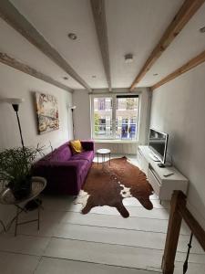 a living room with a purple couch and a tv at 't Kleinste huisje van Arnhem in Arnhem +12 photos