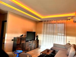 a living room with a couch and a tv at Appartement moderne à Marrakech Piscine, Jardin & fibre in Marrakech