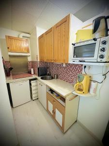 een kleine keuken met houten kasten en een magnetron bij Centre ville Appartement 4 personnes in Cauterets