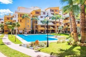 an apartment complex with a swimming pool and palm trees at CC8 III by ZANIS in Torrevieja