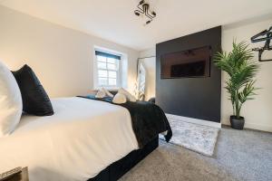 a bedroom with a large white bed and a plant at Modern Town House In Cockermouth in Cockermouth