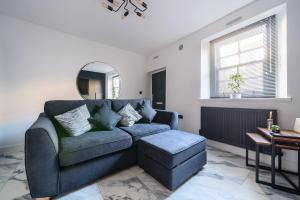 a living room with a blue couch and a stool at Modern Town House In Cockermouth in Cockermouth