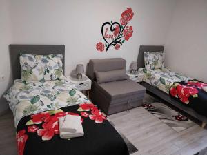 a bedroom with two beds and a chair at AUTOMOTODROM GROBNIK - Apartments and Rooms Skejić in Čavle