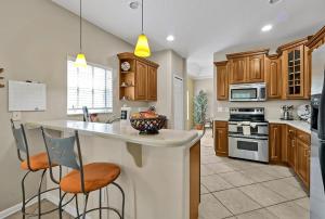 a kitchen with wooden cabinets and a island with bar stools at Entire home w/ Private Pool,Gated Near Disney in Orlando