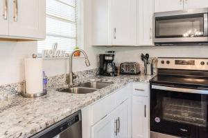 une cuisine blanche avec un évier et un micro-ondes dans l'établissement Cottage in the Pines, à Dauphin Island