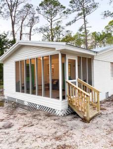 a screened in porch on a white house at Cottage in the Pines in Dauphin Island