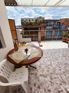 einen Glastisch und weiße Stühle auf dem Balkon in der Unterkunft Apartamento Familiar, cerca al Aeropuerto in Bogotá