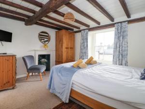 a bedroom with a bed and a chair and a window at The Old Post Office in Ampleforth