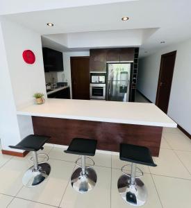 a kitchen with a white counter and two bar stools at DELUXE Apartamento Urbano in Santa Cruz de la Sierra