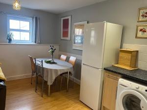 a kitchen with a table and a white refrigerator at Quiet cottage, Ryan Anglesey in Holyhead