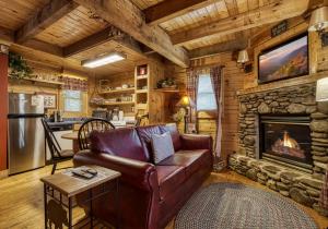 a living room with a leather couch and a fireplace at Tennessee Twilight Cabin in Sevierville +15 photos