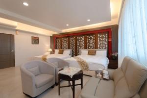 a bedroom with two beds and a couch and a chair at 宜蘭小綠丘民宿 in Luodong