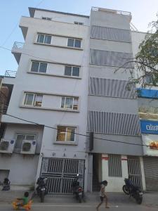 a person walking in front of a tall building at Golden Rooms banglore in Bengaluru