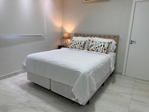 a bedroom with a large bed with a white comforter at Novo e Moderno Apartamento in Boa Vista