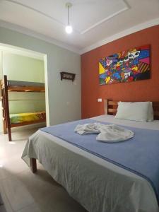 a bedroom with a blue bed with a painting on the wall at Pousada Aconchego do Porto in Porto De Galinhas