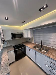 a kitchen with a sink and a stove top oven at Apartamento de Lujo in La Estrella +21 photos