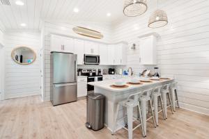 a kitchen with white cabinets and a large island with bar stools at Brand New Luxury Rental on Oleander Unit D in Dauphin Island