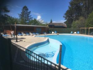 a large swimming pool with a fence around it at Chalet en bois in Bias