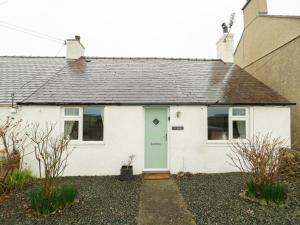 a white house with a green door at Ty Bach in Rhosneigr