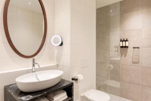 a white bathroom with a sink and a mirror at Corendon Amsterdam Schiphol Airport, a Tribute Portfolio Hotel in Badhoevedorp
