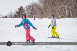 two people are skiing down a snow covered slope at Le Plein Sud - Your ideal getaway by Lake Lise in Chertsey