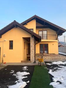 a yellow house with a balcony and a yard at Vila Dor de Munti in Râşnov