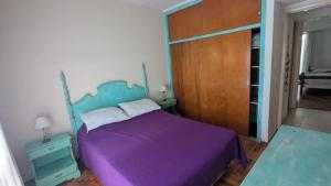 a bedroom with a purple bed and a wooden door at Depto Playa Grande in Mar del Plata