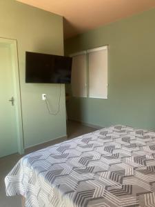 a bedroom with a bed and a flat screen tv at Suíte 3 Praia do Grant in Barra Velha
